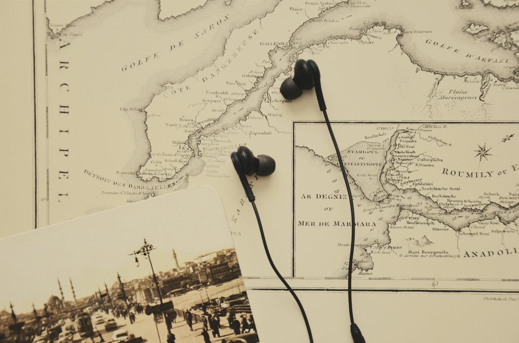 A vintage map with earphones and a historical photograph evoke a blend of history and modern technology.